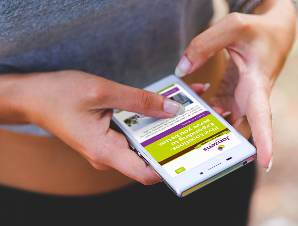 A woman browses Janzen's Pharmacy website on a phone